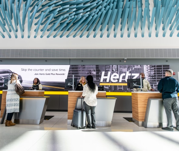 Customers pick up their rental cars at the Hertz service counter.