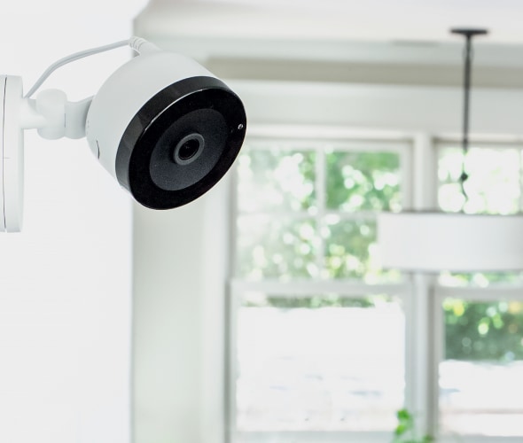 An indoor security camera mounted on a white wall in a modern home.