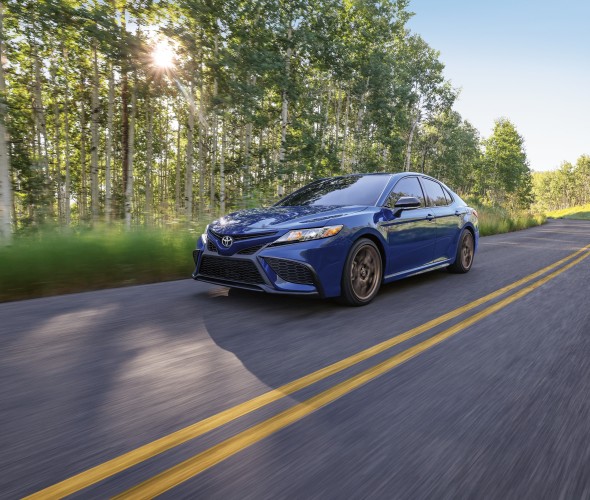 2023 Toyota Camry Hybrid SE Nightshade on a tree-lined road.