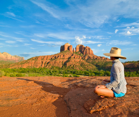 A woman sits on a red rock in Sedona, Arizona.