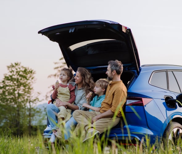 A family sits in the hatchback of their blue electric SUV