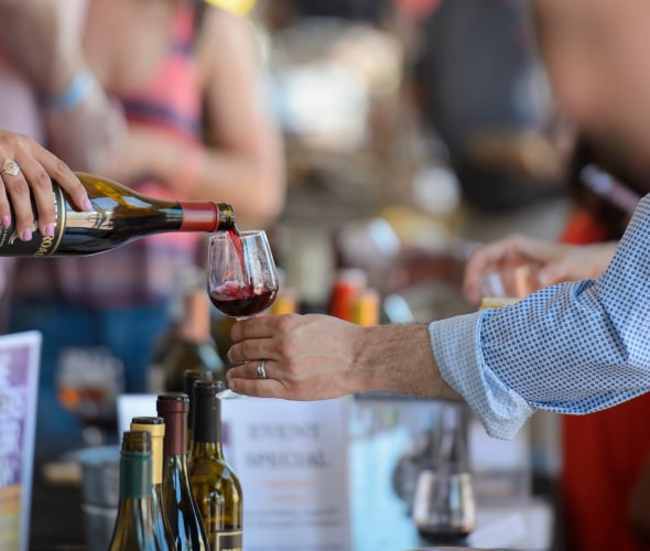 A vendor pours a glass of wine for a visitor at the Monterey Wine Festival in California.