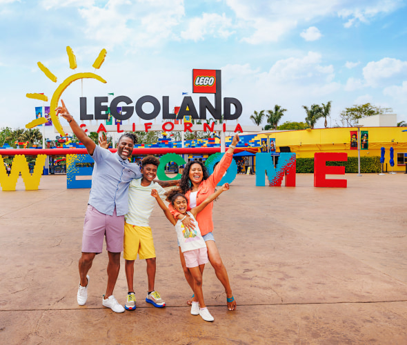 a family takes a fun photo in front of the entrance to LEGOLAND California.