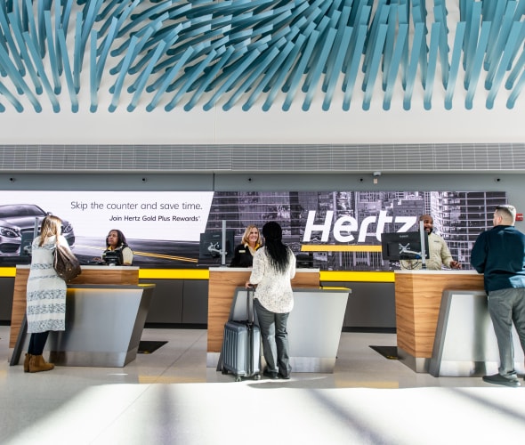 Customers pick up their rental cars at the Hertz counter.