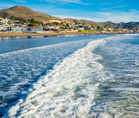 Gentle waves crash onto Cayucos State Beach on the waterfront of Cayucos on the Central Coast of California.