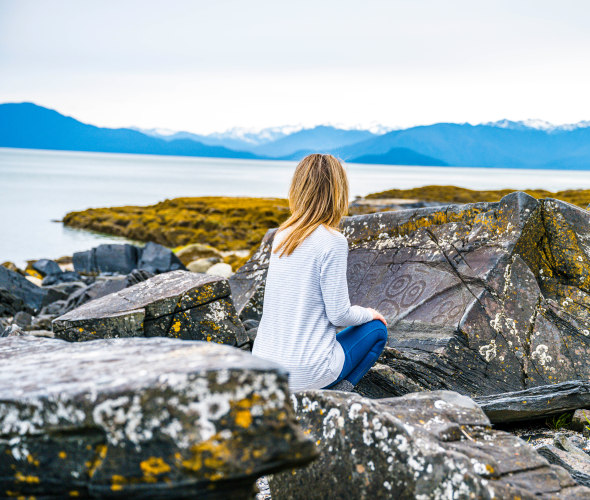 A woman looks at a rock at Petroglyph Beach State Historic Site in Wrangell, Alaska.