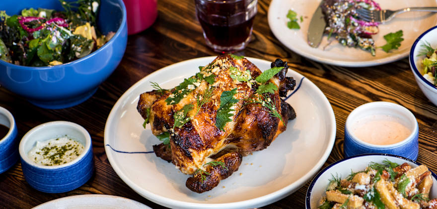 A full rotisserie chicken and sides on a table at RT Rotisserie in Hayes Valley, San Francisco