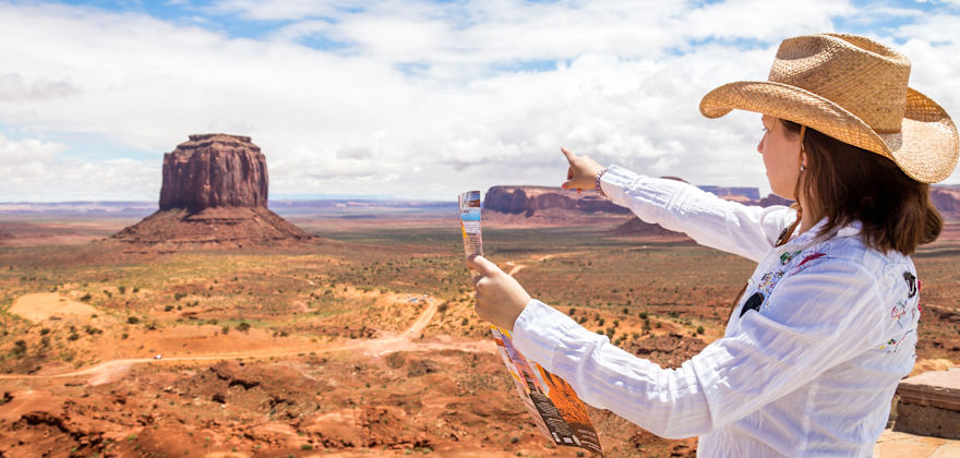 Woman in straw hat points to Monument Valley in Utah