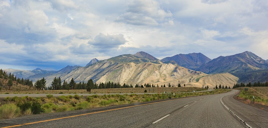The pavement of Highway 395 in Northern California stretches towards the mountains in the distance.