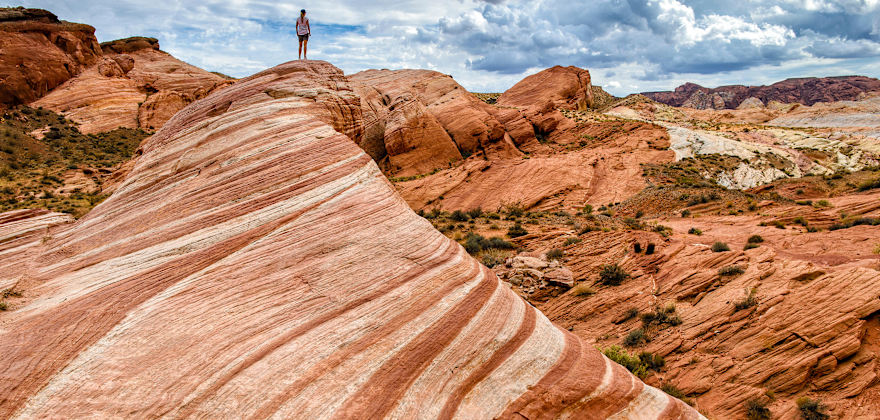 dramatic Fire Wave sandstone formation with woman standing in distance at Valley of Fire State Park in Moapa Valley, Nevada