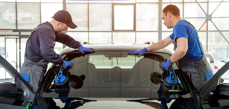Windshield replacement specialists install new glass on a small car.