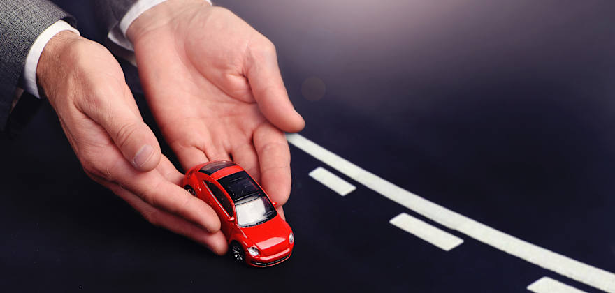 Two hands placing a red toy car on a road