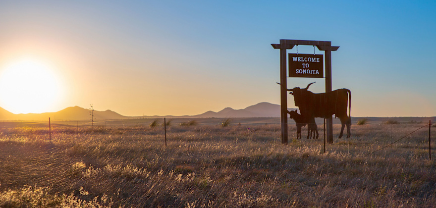 pair of steel longhorns welcomes travelers to Sonoita, Arizona, as sun sets in the background