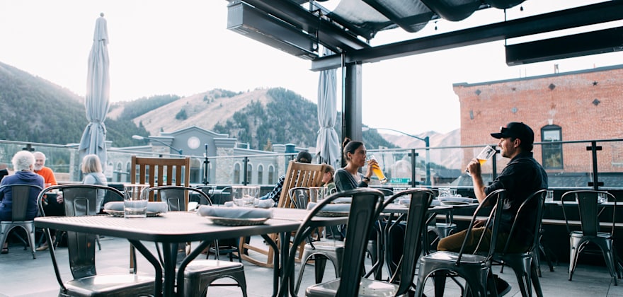 Warfield Distillery rooftop bar guests sip drinks beneath the covered seating area in downtown Ketchum, Idaho