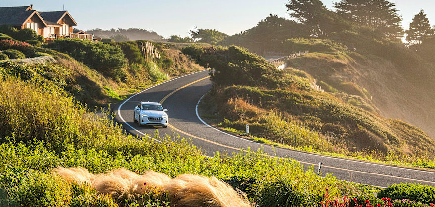 An Audi E-Tron sedan navigates a curve along the coast on a sunny afternoon near Mendocino, California