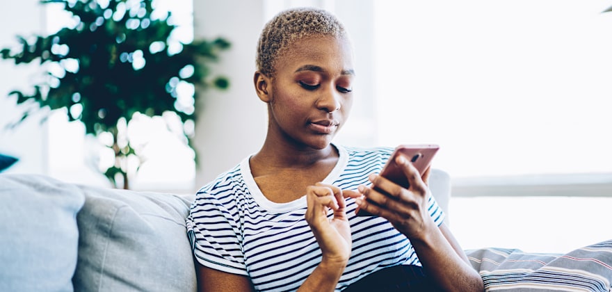 A woman uses her cell phone on the couch.