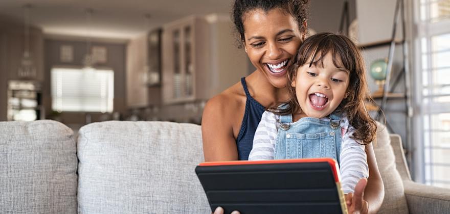 A mom and her child play together on a tablet.