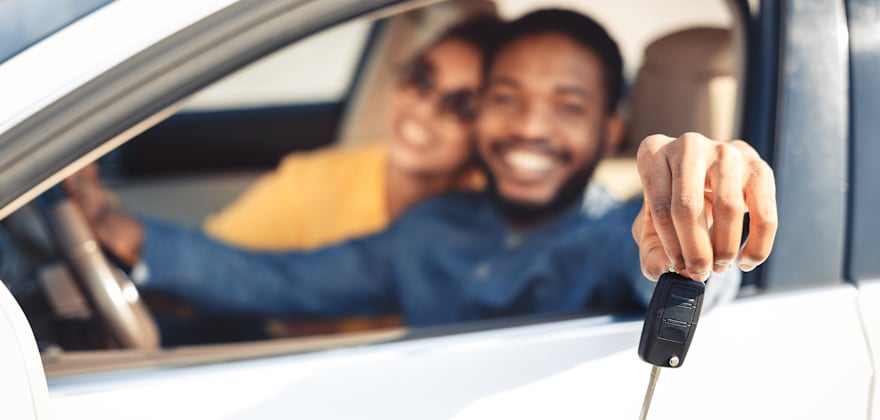 A couple hold the keys to their new sedan.