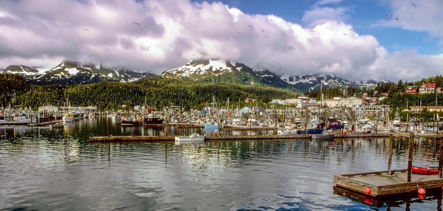 fishing boats in a harbor ringed by snowy mountains