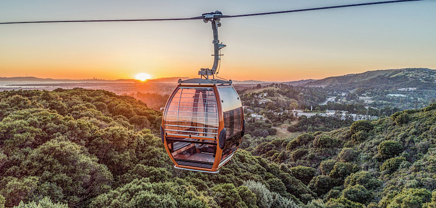 Oakland Zoo Gondola with the Oakland Hills and a sunset in the background.