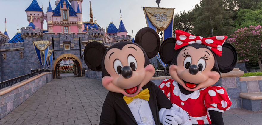 Mickey Mouse stands before Sleeping Beauty's Castle in Disneyland.