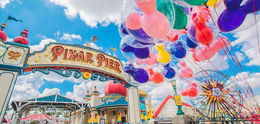 colorful Mickey Mouse balloons float in front of the pixar pier sign at california adventure.