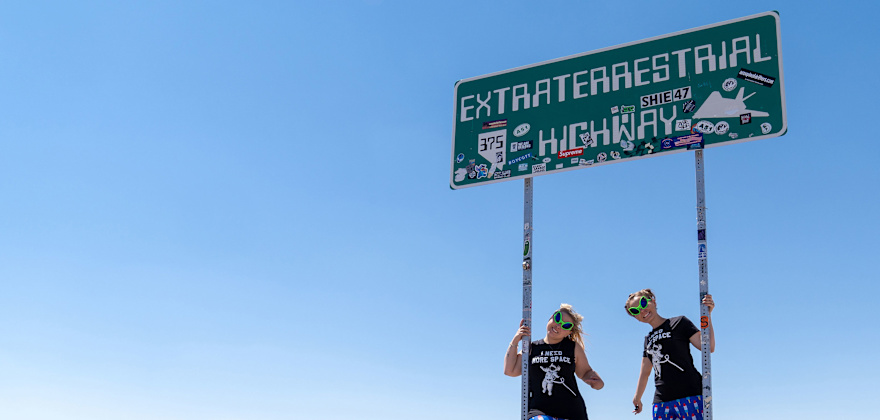 Two road-trippers pose under the Extraterrestrial Highway sign in Nevada.