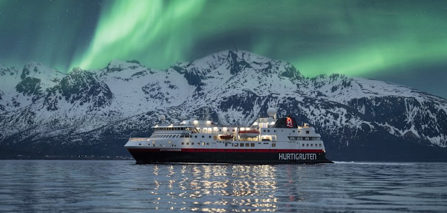 A Hurtigruten Cruise sails under the northern lights.