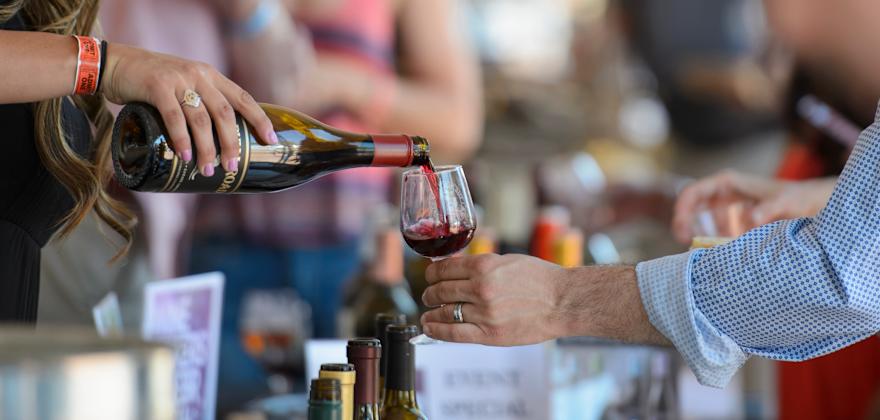 A vendor pours a glass of wine for a visitor at the Monterey Wine Festival in California.