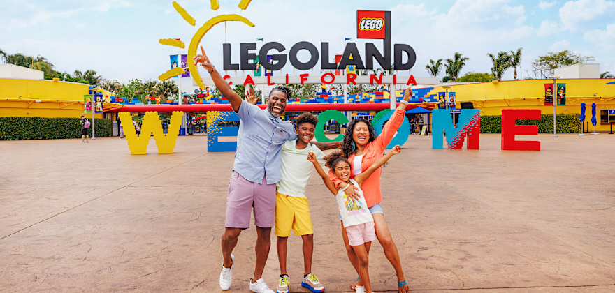 a family takes a fun photo in front of the entrance to LEGOLAND California.