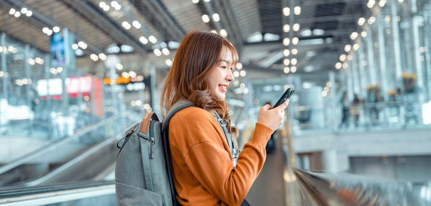 A woman uses the mobile passport control app on her phone as she walks through the airport.