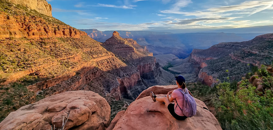 Rear view of woman sitting on rock along Bright Angel trail overlooking South Rim of Grand Canyon National Park, Arizona.