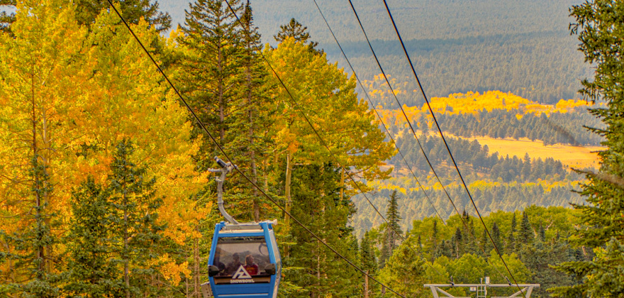 A gondola goes up the hill at Arizona Snowbowl with fall color in the background.