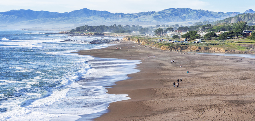 People walk along the sand at Moonstone Beach in Cambria, California.
