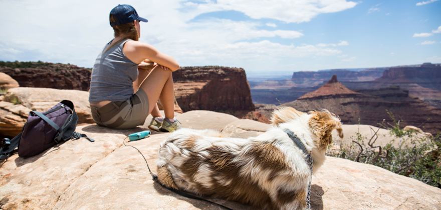 A hiker sits with her Australian Shepherd puppy in Utah's dog-friendly Dead Horse Point State Park.