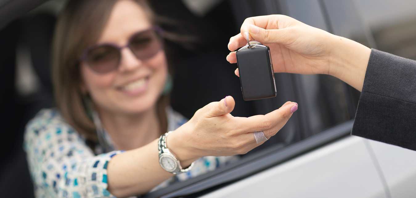 someone hands over keys to a happy new car owner after participating in the AAA Auto Buying Program