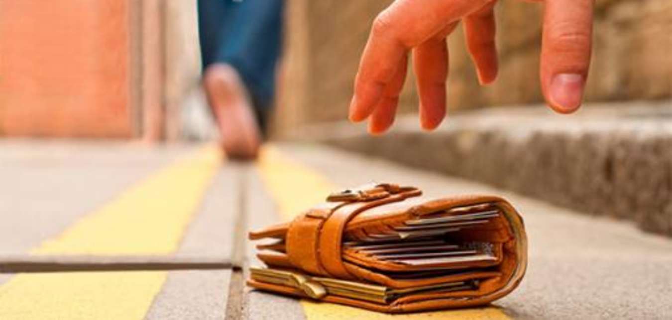 a person picks up a wallet from the ground