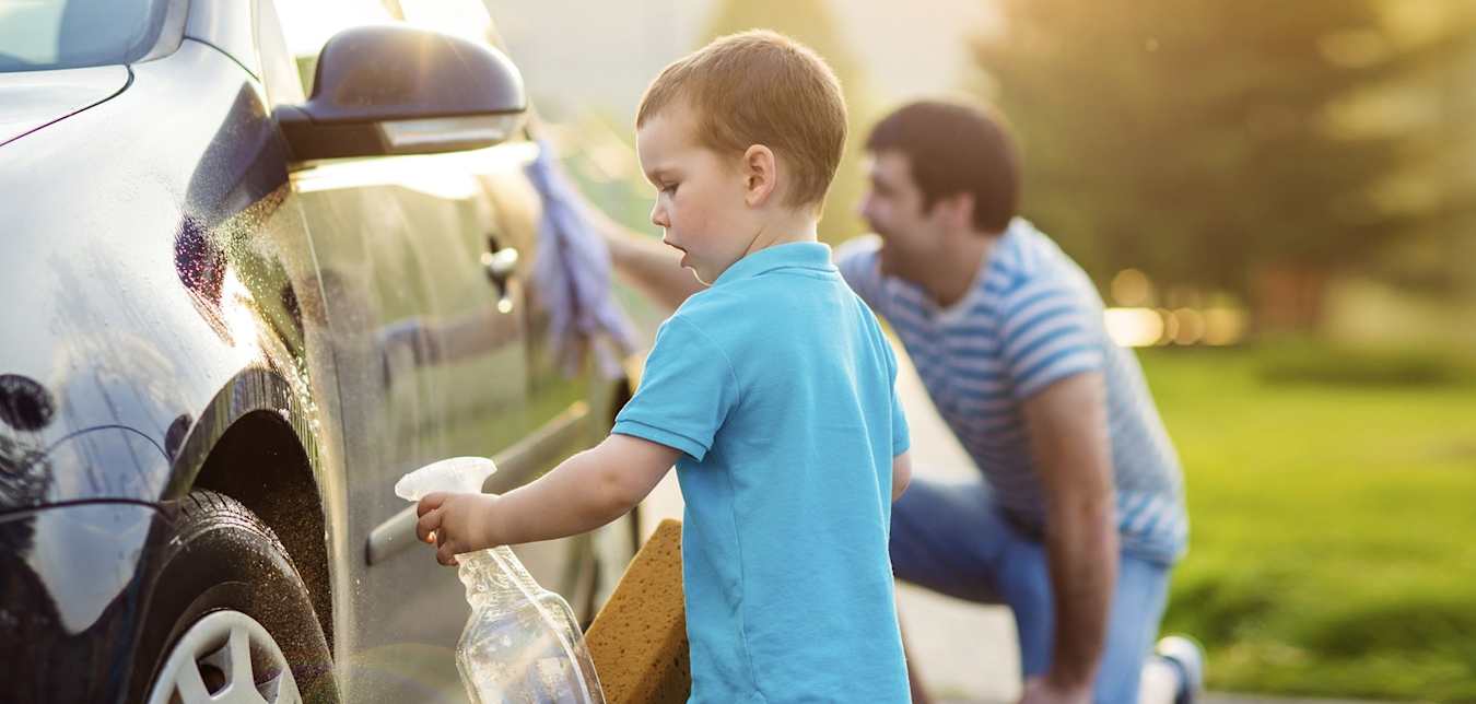 little boy washes a car with his father, a AAA insurance policy holder