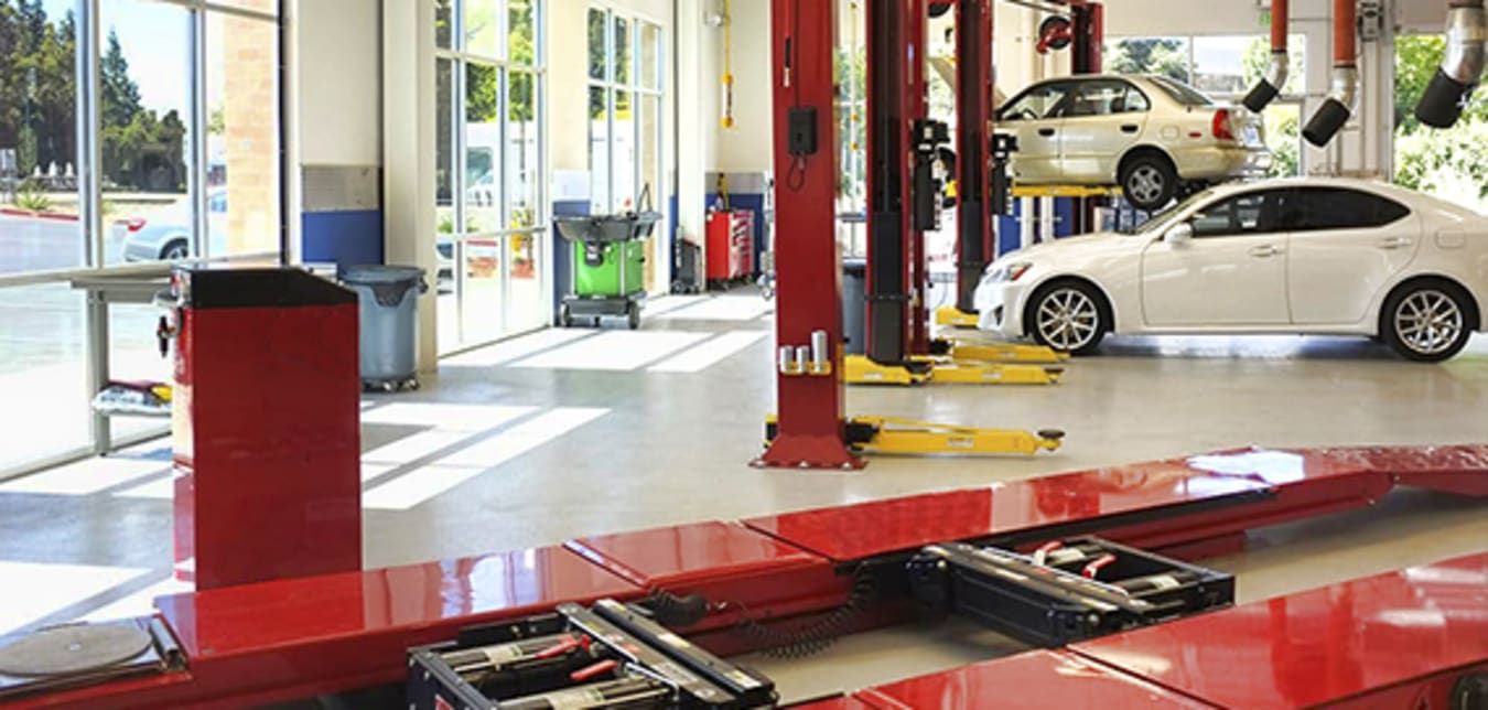 Inside of a AAA Auto Repair Center with car lifts and multiple cars.