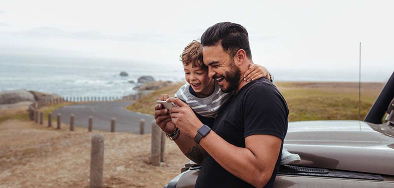 a AAA Member and his young son look at photos on a coastal road trip