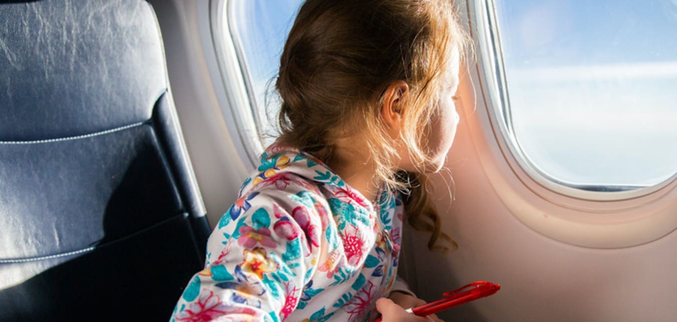 Kid flying in airplane looking out of the window