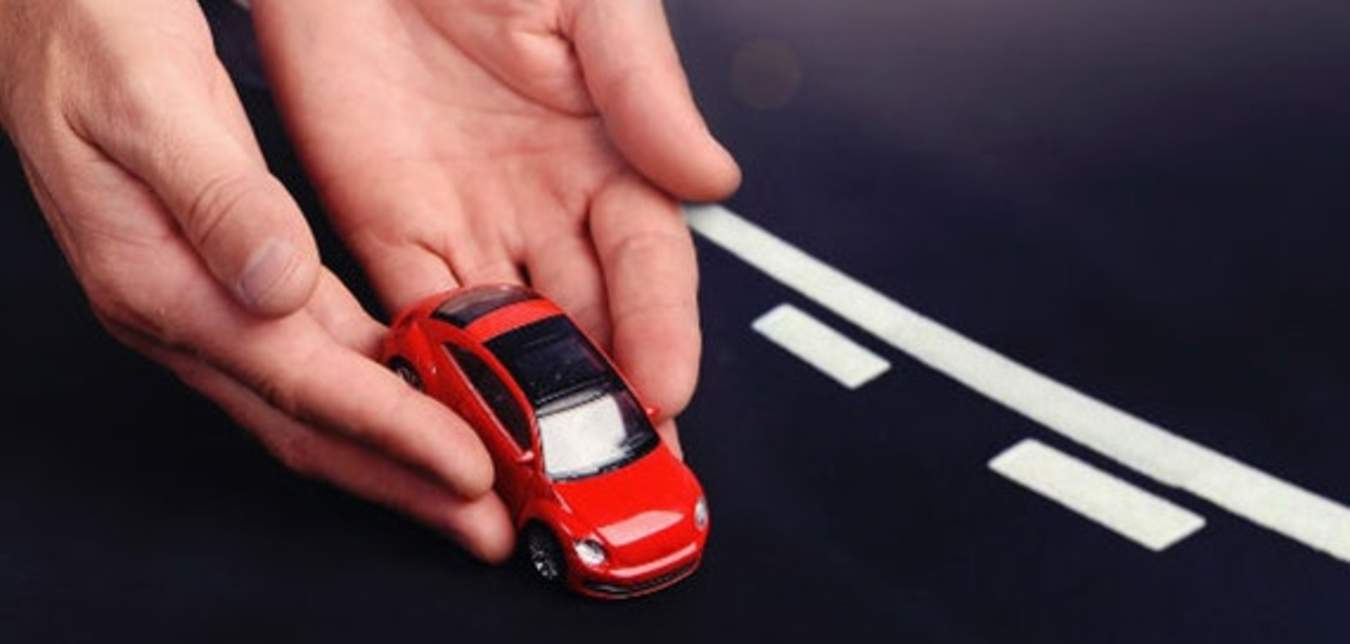 AAA insurance policy holder's hands placing a red toy car on a road.