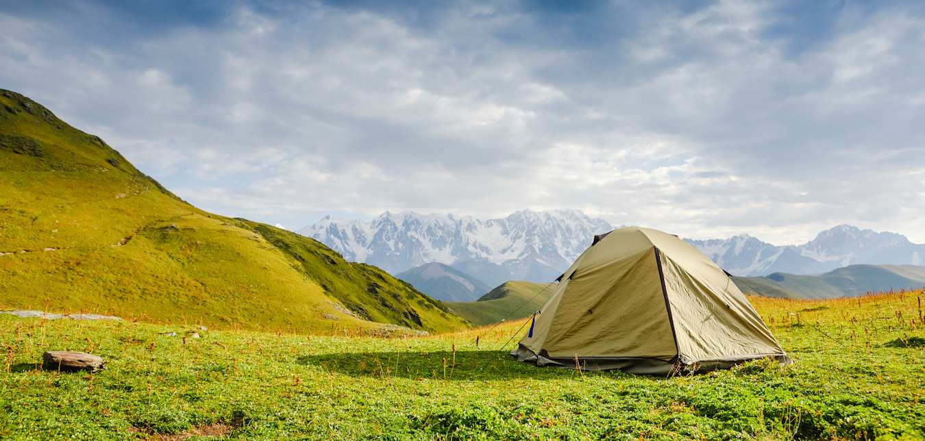Pitched tent on the grass overlooking beautiful view.