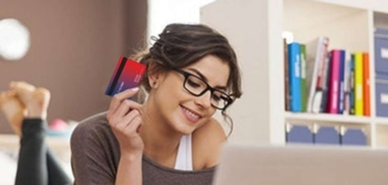 woman on the floor holding her AAA Membership card while on her laptop