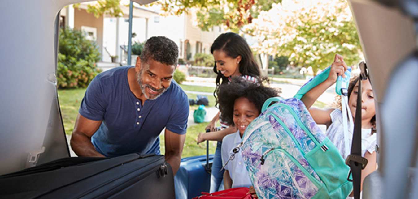 family placing luggage in dollar rental car