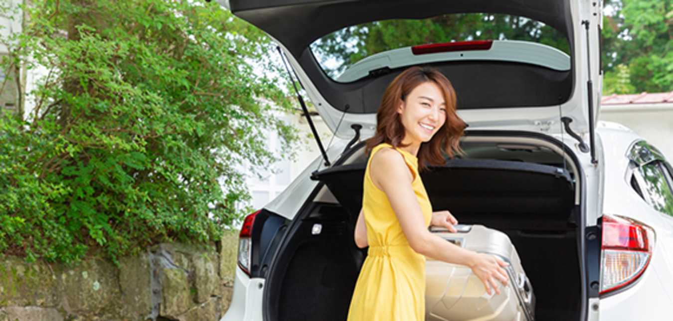 woman loading suitcase in to thrifty rental car