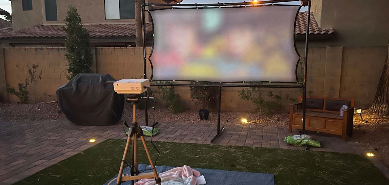 A projector plays a movie on a DIY projector screen.