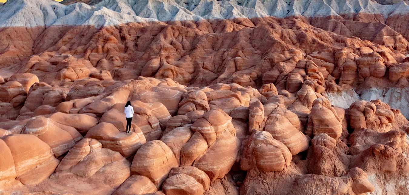 A woman stands on the badlands in Grand Staircase Escalante National Monument.