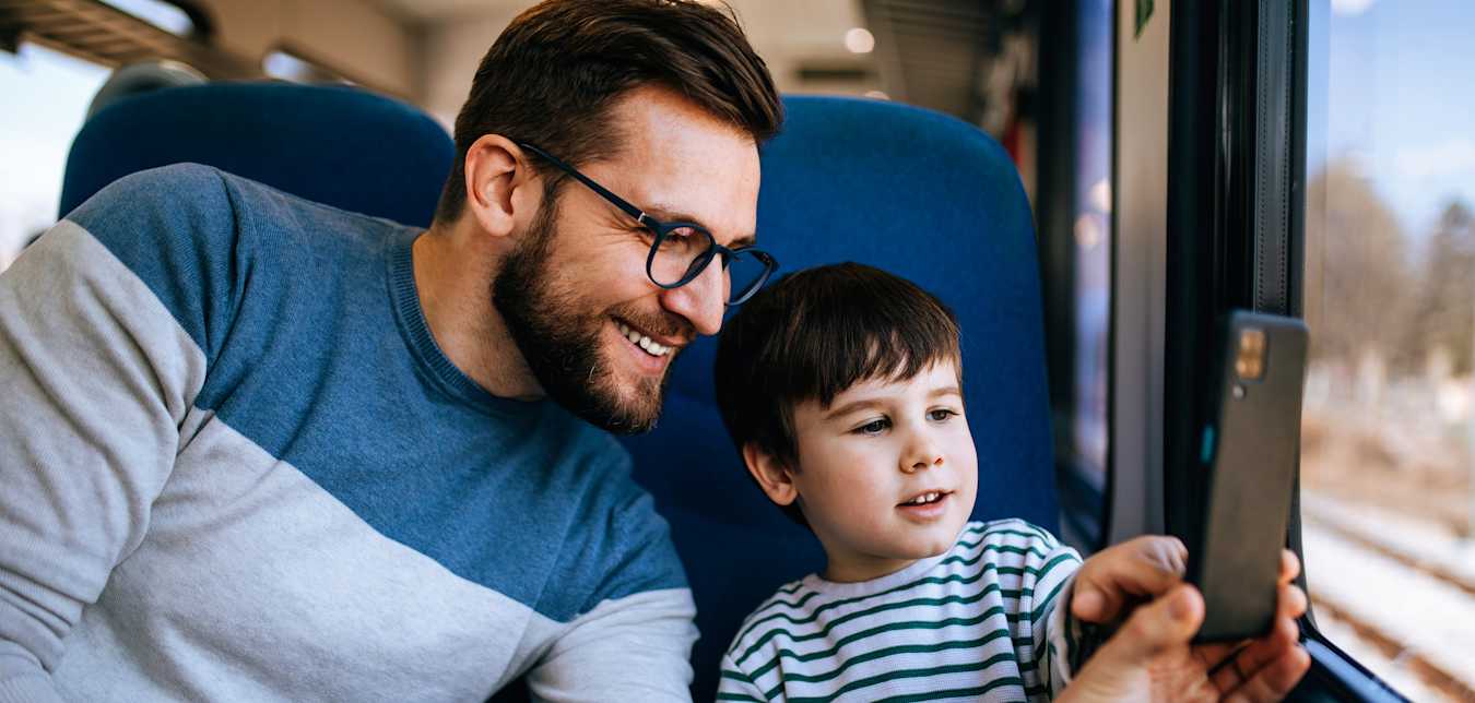 A father and son read Via Magazine while riding on a train.
