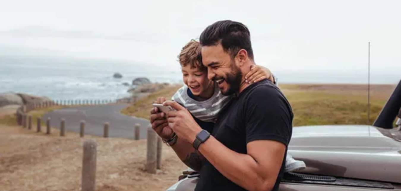 Man and boy looking at phone on the coast